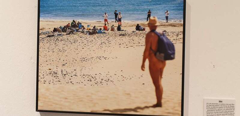 Un turista europeo desnudo observa a un grupo de migrantes llegados a las Dunas de Maspalomas / Borja Suárez